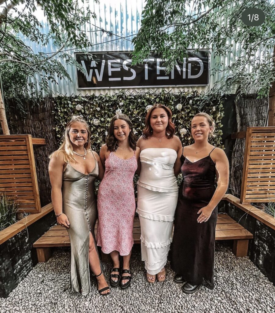 Person smiling in front of the Westend event and function venue Christchurch Big screen in background
