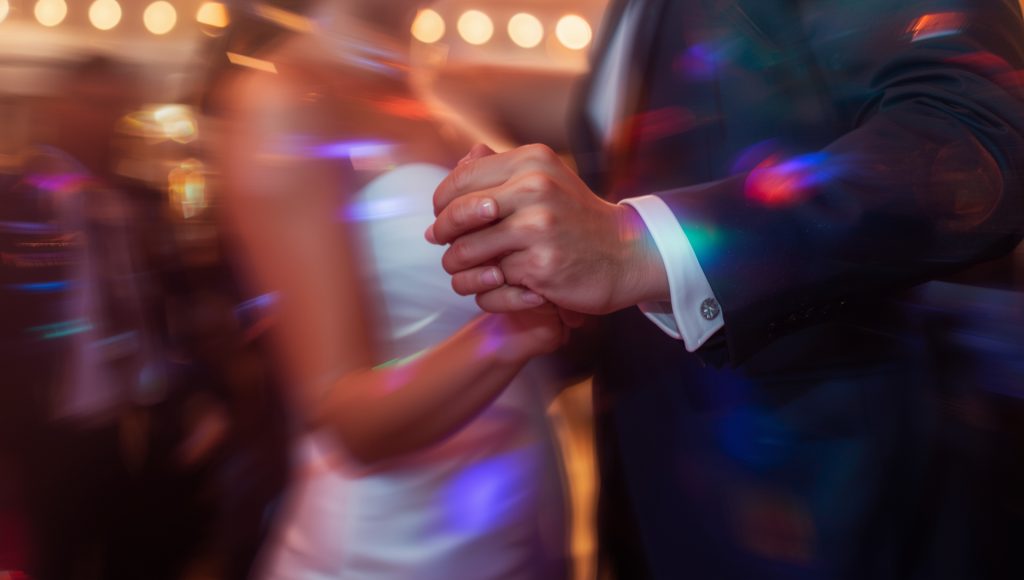 Close-up of a couple dancing at a Christchurch wedding with soft motion blur and colourful lights.